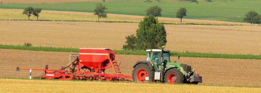 Traktor mit Sämaschine bei der Aussaat auf einem Feld bei Goldbach